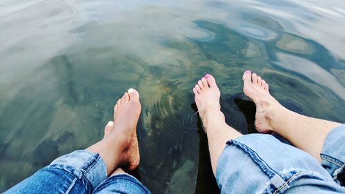 Low section of friends sitting over lake