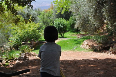 Rear view of boy standing against trees