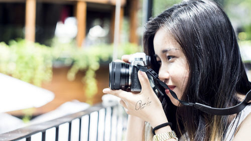 Portrait of young woman photographing with camera