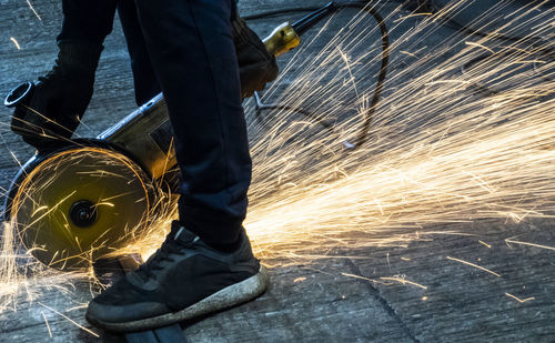 Low section of man using grinder at workshop