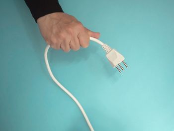 Close-up of hand holding paper against blue background