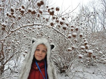Close-up portrait of girl standing against snowcapped trees