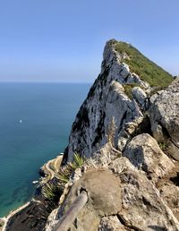 Rock formation in sea against clear sky