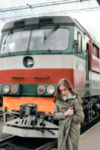 Woman standing by locomotive at railroad station platform