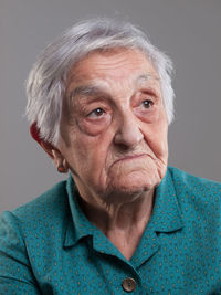 Thoughtful senior woman against gray background