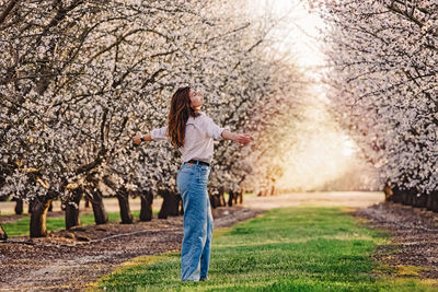 Woman enjoying springtime outdoors among blooming almond trees, allergy free concept