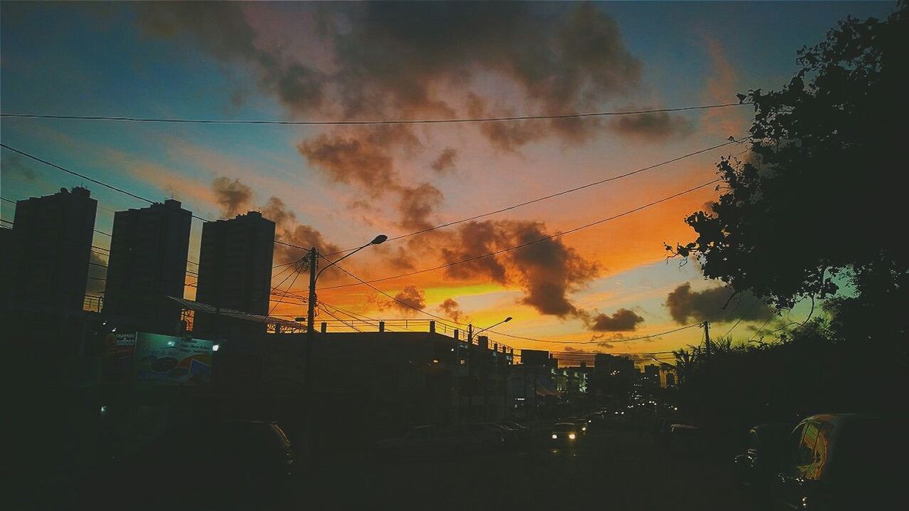 sunset, building exterior, architecture, city, sky, built structure, silhouette, car, transportation, land vehicle, cloud - sky, orange color, street, mode of transport, street light, city life, dusk, building, traffic, road