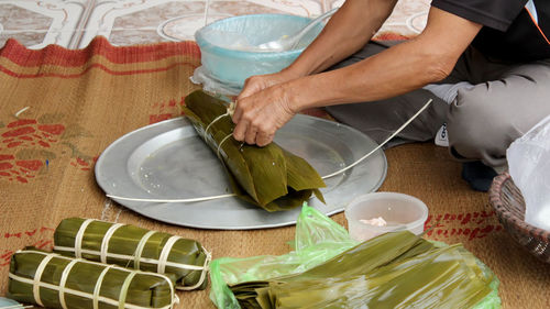 Low section of man packing food in leaves on tray