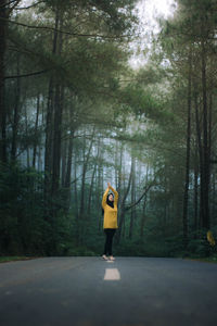 Man standing on footpath amidst trees in forest