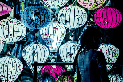 Rear view of woman standing in illuminated market