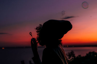 Silhouette woman against sea during sunset