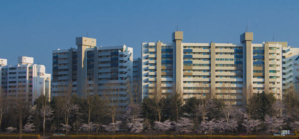 Buildings in city against clear blue sky