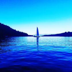 Sailboat sailing in sea against clear blue sky