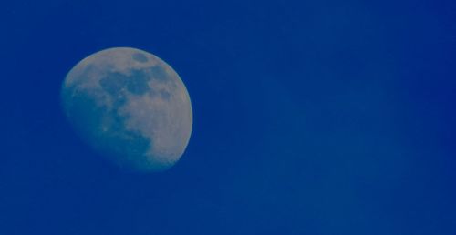 Low angle view of moon against clear blue sky