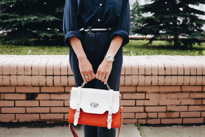 Midsection of woman holding bag at park