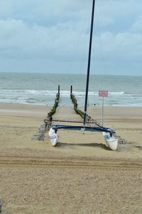 Deck chairs on beach against sky