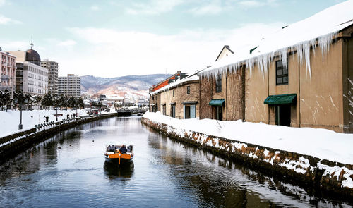 Scenic view of river amidst buildings against sky during winter