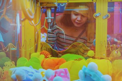 Portrait of smiling young woman looking at the claw machine