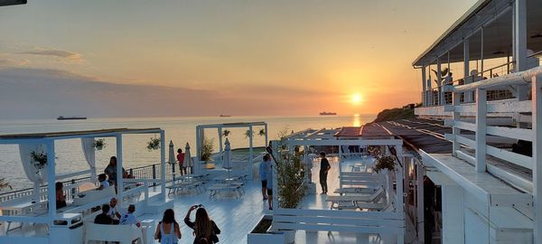 People at swimming pool against sky during sunset