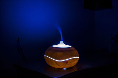Close-up of illuminated electric lamp with smoke on table