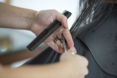 Cropped image of female hairdresser cutting woman hair