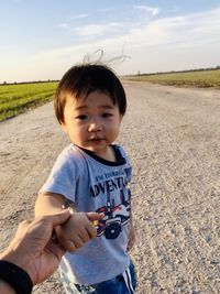 Portrait of cute boy lying on land against sky