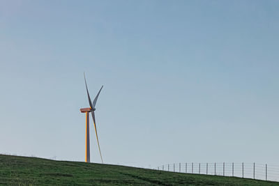 Wind power turbine on the green hill lighted with a warm morning sunlight. sustainable energy