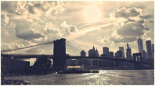 Bridge over river against cloudy sky