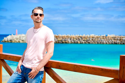 Portrait of man wearing sunglasses standing against sea