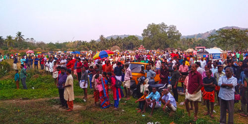 Crowd on grass against clear sky