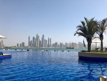 Scenic view of swimming pool by buildings against clear sky