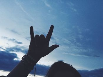 Low angle view of human hand against sky