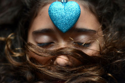 Close-up of woman with blue glitter heart on forehead