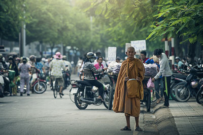 Portrait of monk standing on road in city