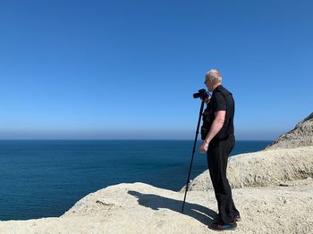 Man standing in sea against clear blue sky