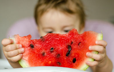 Child holding slice of watermelon against face