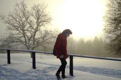 Full length side view of man standing on snow covered landscape