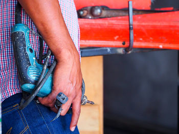 Midsection of worker holding equipment