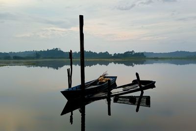 Wooden post in lake against sky during sunset