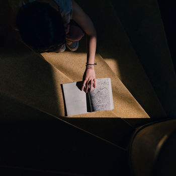 HIGH ANGLE VIEW OF WOMAN SITTING ON PAPER