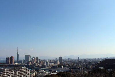 Aerial view of buildings in city against clear blue sky