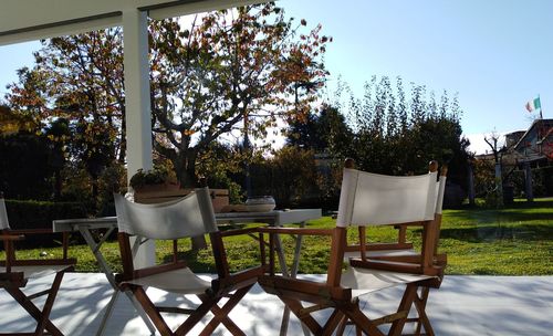 Empty chairs and table in yard against clear sky