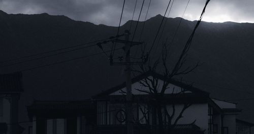 Low angle view of silhouette electricity pylon against sky