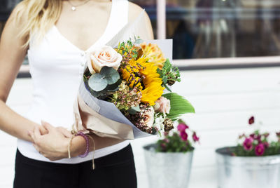 Midsection of woman holding flowers