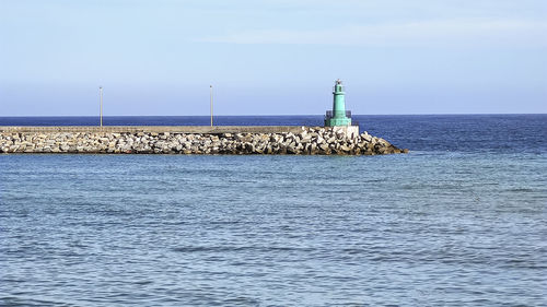 Lighthouse by sea against sky