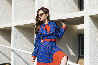 Young woman looking away while standing against building