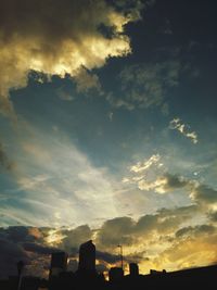 Silhouette of city against cloudy sky