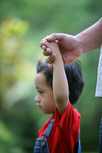 Cropped hand of father holding son at back yard