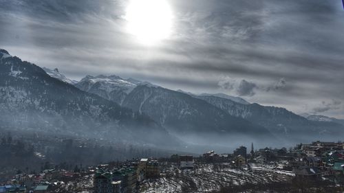 Aerial view of townscape and mountains against sky