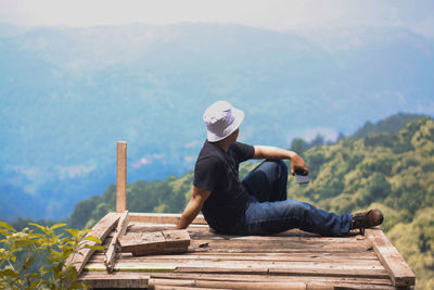 Man sitting on bench against mountains